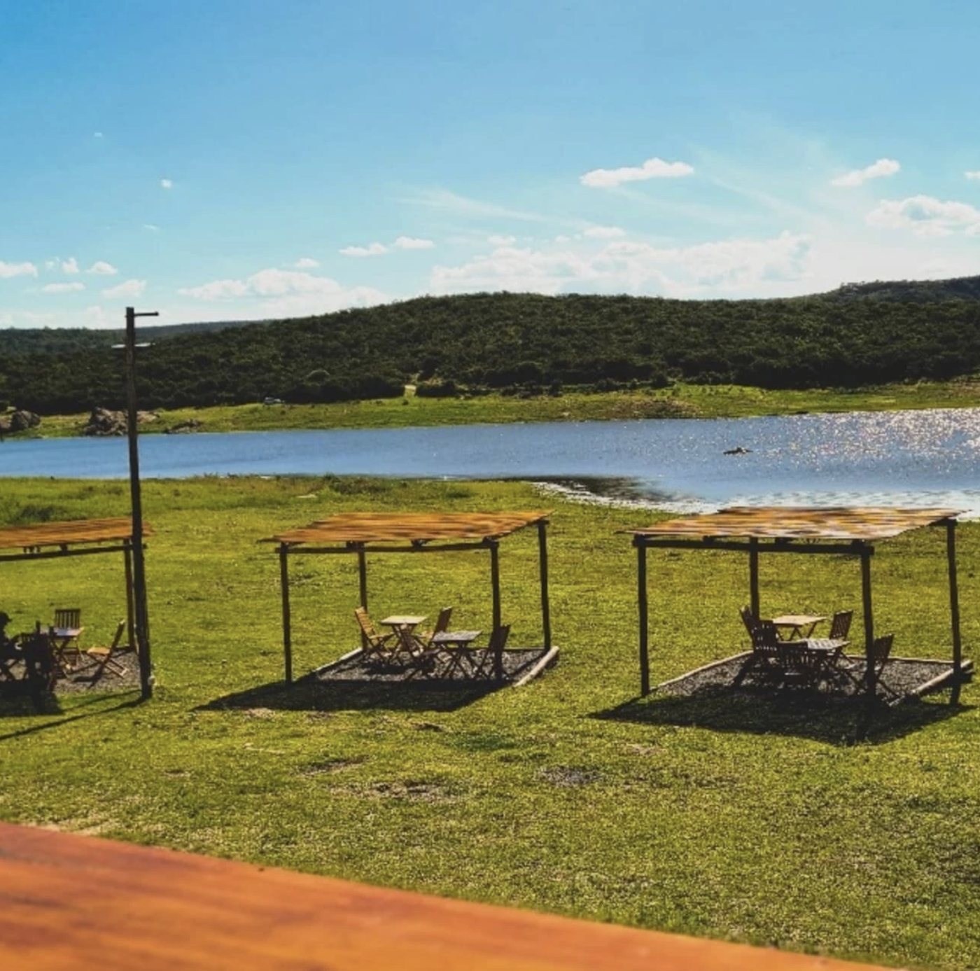 Pérgolas de madera con mesas frente al dique